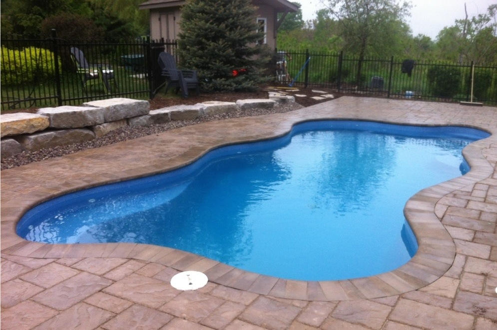 Beautiful fiberglass swimming pool with stone patio